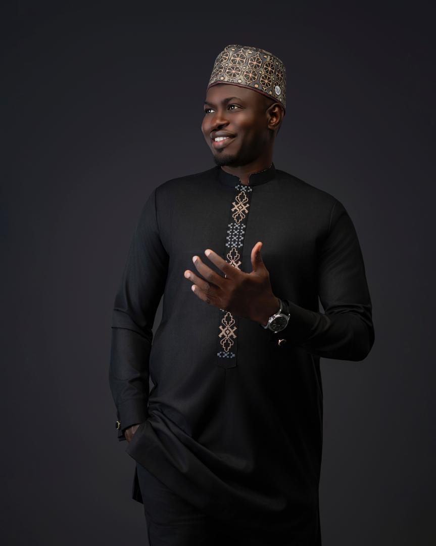 Homme en tunique noire à broderie géométrique et calotte